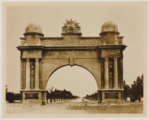 Stone archway at the entrance to a tree lined avenue. Archway bears text and the years 1914 1918.