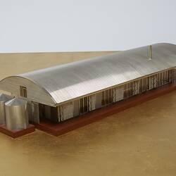 Model of a house with an arched roof, corrugated iron and wide expanses of glass.