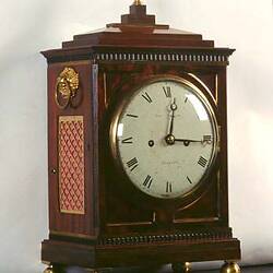 Brown wooden clock set to 15 minutes past 12.