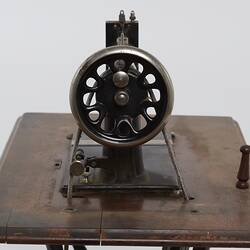 Detail of sewing machine fitted to a metal frame with a wooden bench.
