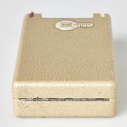 Rectangular cream metal case with hinged lid. Closed.
