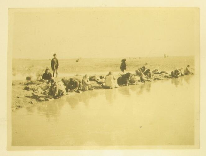 Dhobies washing clothes along river bank.