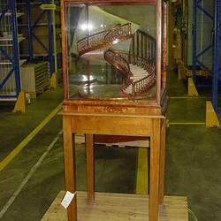 Model of a wooden staircase in a glass case.