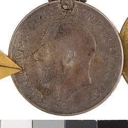 Round medal with profile of a man and text surrounding.