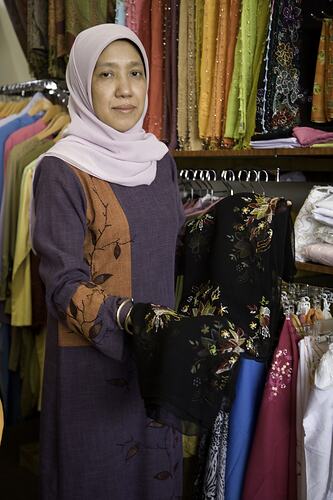 Woman posing with clothing in a clothing store.