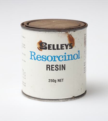 White tin with rusted lid. Blue and black printing on label.