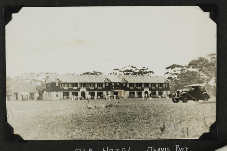 Group of people playing sport on lawn in front of building.