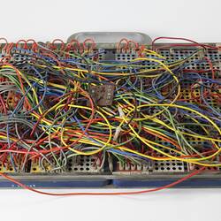 Metal board with messy coloured wires.