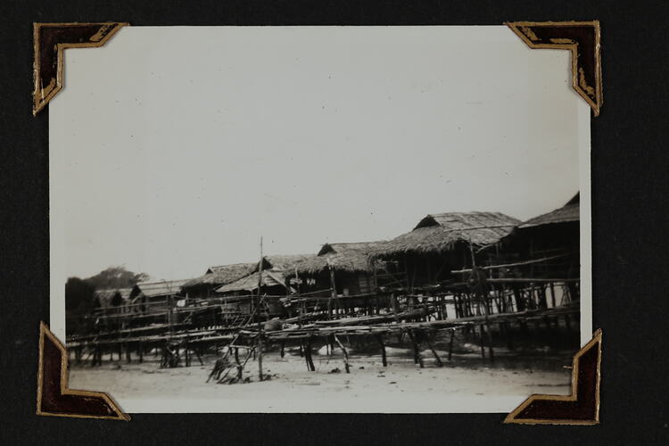 Row of thatched beach huts on stilts.