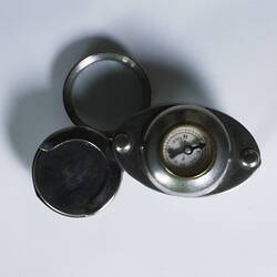 Plated oval plates joined by two pins, small compass in domed top.
