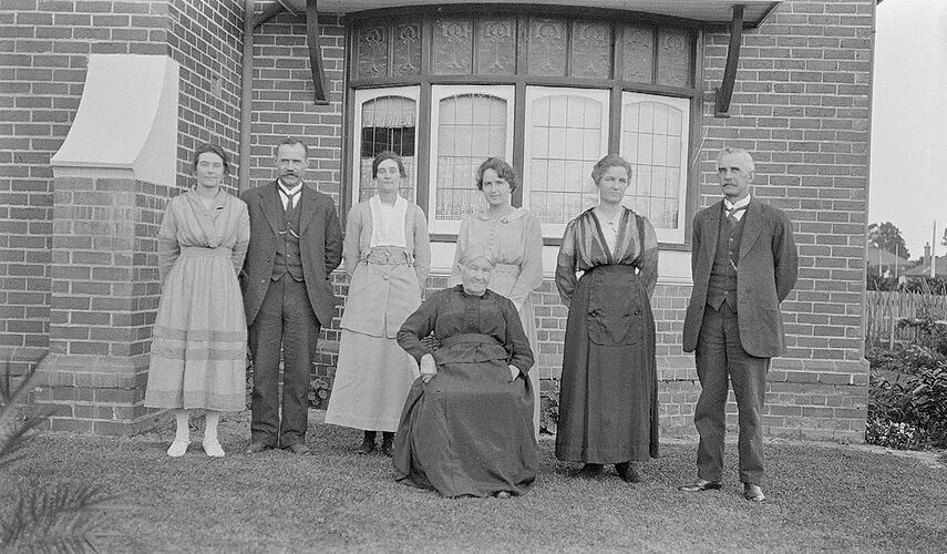 Monochrome negative of a group near a house.