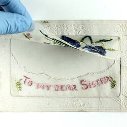 Front of embroidered postcard with front panel lifted.