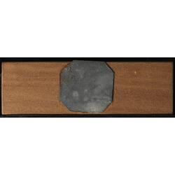 Underside of wooden microslide with octagonal metal central panel.