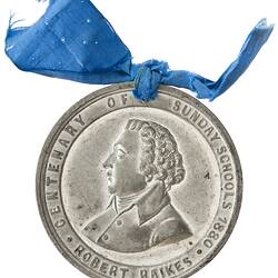Round silver medal with bust of man facing left. Suspended from blue ribbon.