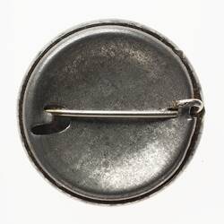 Round metal badge with horizontal pin.