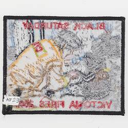 Back of cloth badge with image of firefighting man in yellow feeding water to a koala.