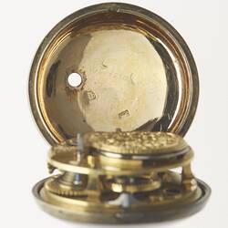 Pocket watch within gilt and tortoise shell case. Open to expose inner lid and decorative mechanism.