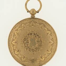 Closed ladies gold pocket watch with ornate design on cover. Ring at top.