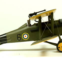 Dark green model airplane. Circle pattern on top on each wing. Right profile.