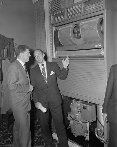 Man presenting an air conditioning unit to another man.