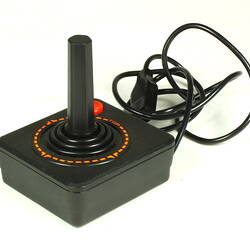 Three quarter view of black plastic joystick showing power cable.