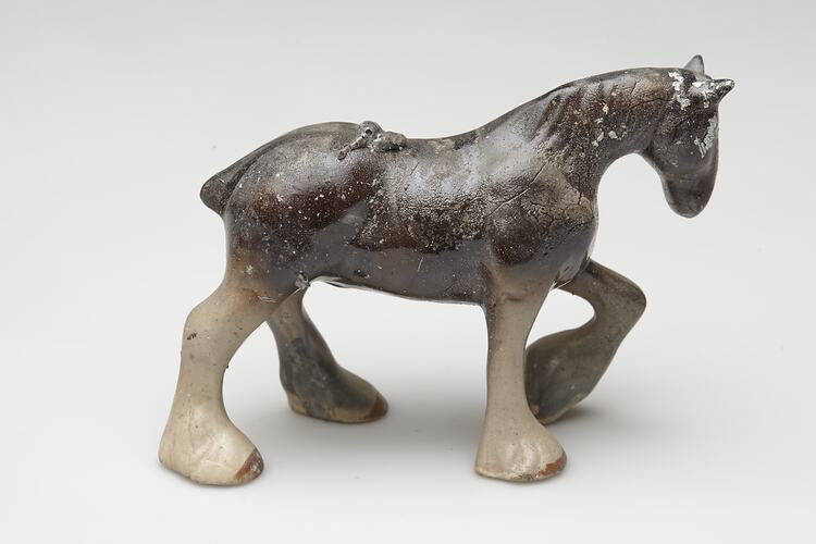 Fire affected brown and cream ceramic horse figurine.