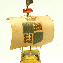 Front view of ship with yellow hull and painted sail.