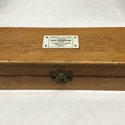 Closed wooden case with label on top.