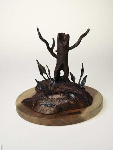 Metal and wood tree-shaped sculpture on round base.