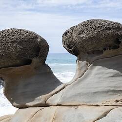 Grey cannonball rocks embedded in rocky shore.