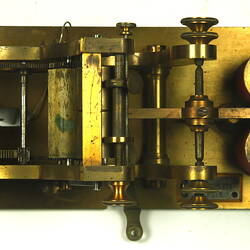 Brass apparatus with batteries on metal base, overhead view.