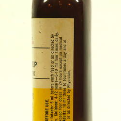 Side of brown glass bottle with white cap.