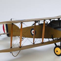Model biplane aeroplane painted mustard brown with grey engine. Three quarter right view, wing section.