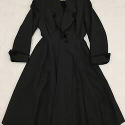 Long coat made from a grey woollen fabric. Laid flat.