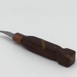Knife with carved dark wooden handle and small blade. Three diagonal lighter wooden strips in handle centre an