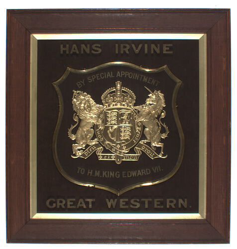 Royal coat of arms in gold on a wooden plaque.