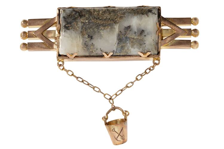 Triple bar brooch with central quartz and gold specimen with small gold bucket attached via chain.