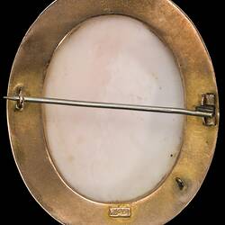 Back of oval white cameo of female bust facing left. She wears a draped garment and has ribbons in her hair. Plain gold setting.