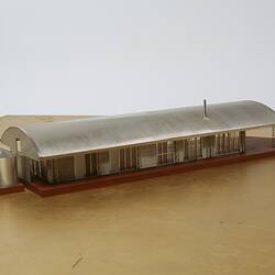 Model of a house with an arched roof, corrugated iron and wide expanses of glass.