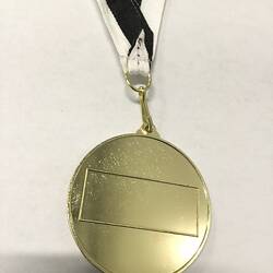 Back of soccer medal with blank inscription panel. Black and white ribbon.
