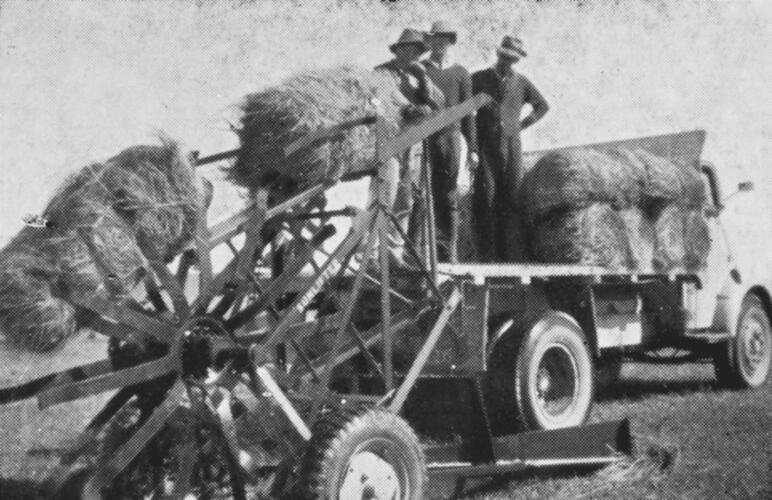 [Lifting hay bales onto a truck using a bale loader, about 1940s.]
