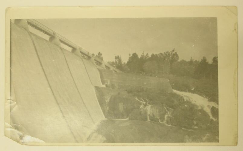 Outer wall of a dam, rocks and trees.