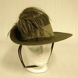 Khaki slouch hat with emu feather decoration on left side.