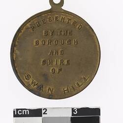Round bronze coloured medal with text surrounding.
