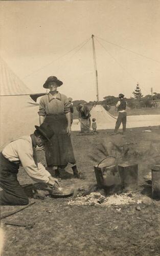 Digital Photograph - Holden Brothers Circus, Man Cooking Over Fire with Woman Watching, circa 1918