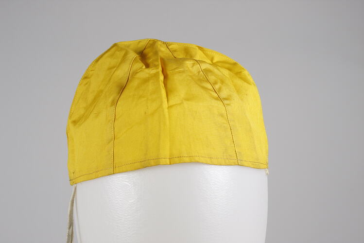Yellow silk hat, conical to follow shape of head.
