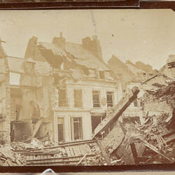 Damaged buildings with wreckage in front.
