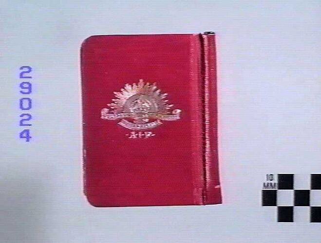 Red book with white Rising Sun emblem in centre, back view.