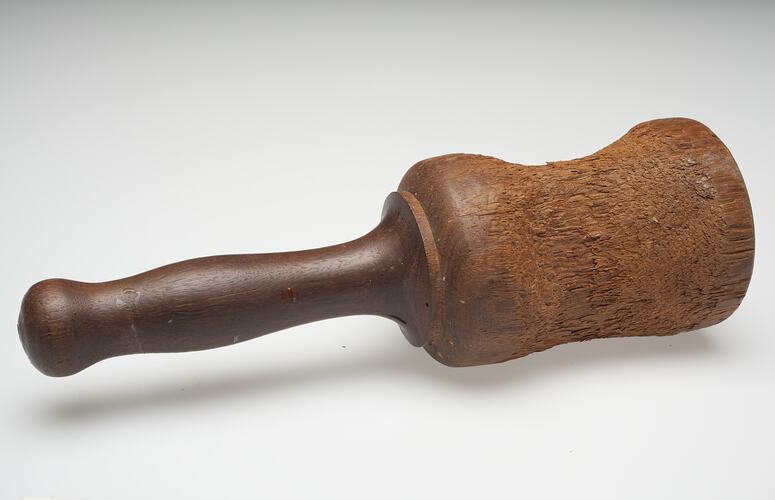 Old wooden Mallet, dented and worn from use. Tapered wooden handle, simple design.