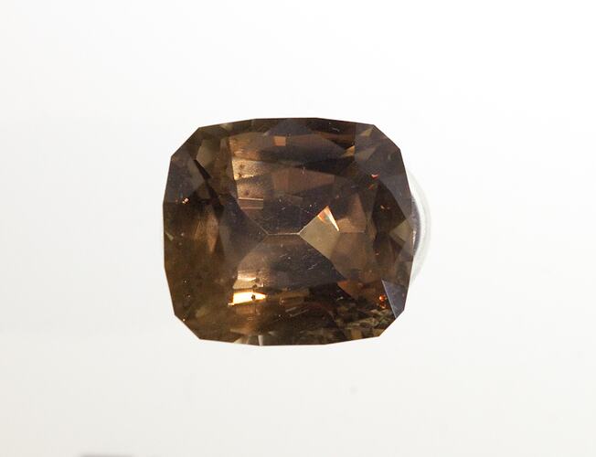 Grey-brown faceted gemstone specimen.